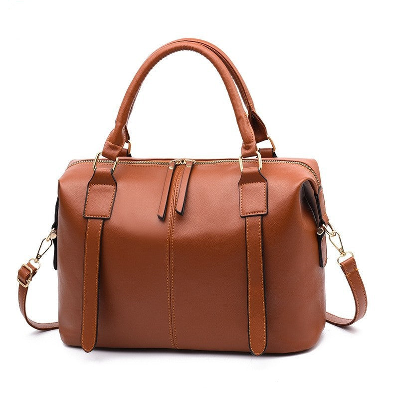 Brown leather handbag with gold accents on a white background